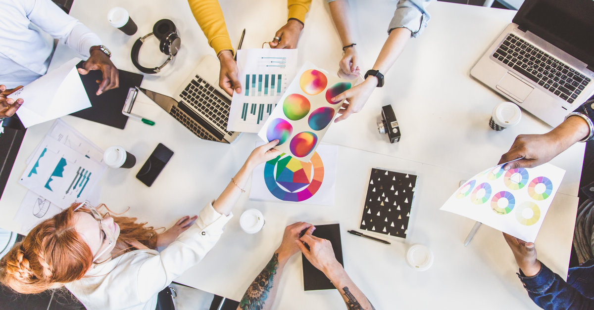 Group of multi ethnic executives discussing during a meeting. Business man and woman sitting around table at office and smiling. A team of young creative designers.